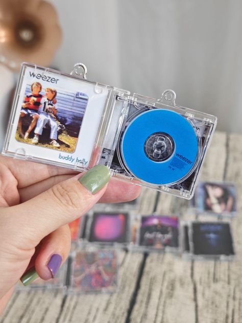 🎶 Custom Mini Album CD Keychain with NFC - Play Your Favorite Spotify Song Anytime, Anywhere! 🎧 Introducing the perfect gift for music lovers! Our Mini Album CD Keychain is more than just a cool accessory--it's a tiny portal to your favorite song. With an embedded NFC chip, simply tap your keychain against your phone, and your chosen song will start playing on Spotify instantly! 📱🎵 How It Works: - Choose Your Song: Copy the Spotify share-link of the song you want on your keychain. 🎶🔗 - Specify Artist & Album: Provide the name of the artist and the album the song is from, and we'll recreate the miniature album cover in stunning detail. 🎨✨ - Get Your Custom Keychain: We'll embed the song into your personalized mini album CD keychain and ship it directly to you! 📦💌 Why You'll Love It Cd Keychain, Music Items, Artist Album, Favorite Song, Cd Album, Album Cover Art, Gift For Music Lover, Played Yourself, Music Gifts