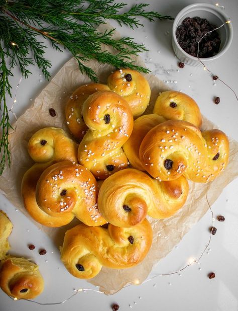 Saffron buns on a piece of parchment paper. Saint Lucia Buns Recipe, St Lucia Buns Recipe, St Lucia Christmas Swedish Traditions, Lucia Buns Recipe, Saint Lucia Day, Sourdough Swedish Cinnamon Buns, Saffron Buns Swedish, Danish Cuisine, Pearl Sugar