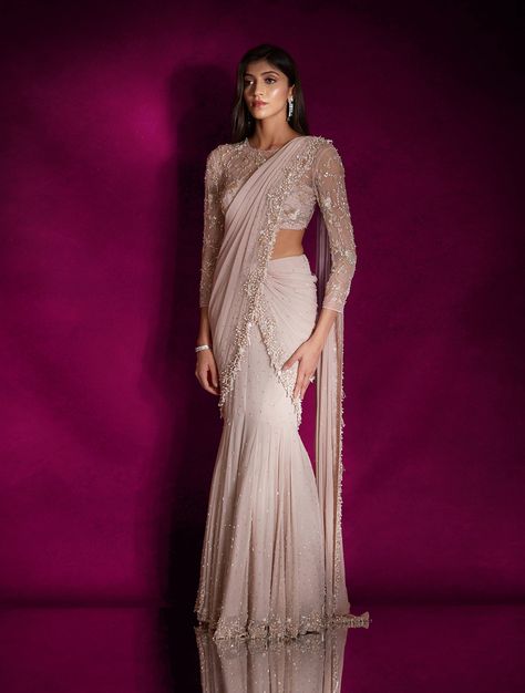 Dusty pink georgette fish style sari heavily hand embellished with pearls, silver glass beads, mixed materials & tassels, paired with a champagne and silver floral embellished sheer blouse featuring an open back.From Shloka Khialani's Winter Sun collection.DELIVERY TIMEPlease allow 6-8 weeks for your outfit to arrive.FABRIC DETAILSGeorgette, NetProfessional cleaning only. Mermaid Lehenga Indian Fashion, Western Saree Party Wear, Mummy Cocktail, Western Sarees Fashion, Outfit For Sangeet Function, Saree With Shrug, Saree Wedding Guest, Western Sarees, Mermaid Saree