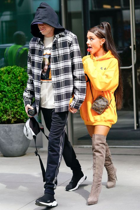 Halloween Couples Costumes Pete Davidson and Ariana Grande Pete and Ariana are all about unseasonable dressing. These outfits, for example, were worn in the dead of summer. The recipe for Pete: graphic tees, track pants, and hoodies. For Ari, an oversized hoodie, over-the-knee boots, and a high pony. (Her look is called lampshading. More on that here.)  ##halloween Ariana Grande Cover, Ariana Grande Tattoo, Pete Davidson, Ariana Grande Outfits, Walking Down The Street, Ariana Grande Style, Yellow Hoodie, Hailey Baldwin, Couple Halloween