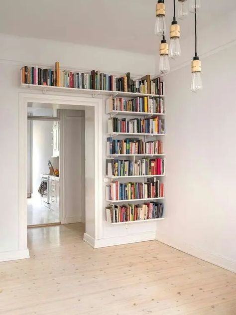 bookshelves covering one wall next to the doorway and a space over it will give you much space for books and will help you declutter the space Book Shelves Above Door, Book Shelf Over Doorway, Book Shelf Around Door, Over Door Bookcase, Books Above Door, Around Door Shelves, Bookshelves Behind Door, Over Door Bookshelves, Around Door Shelving