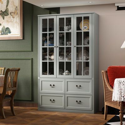 This pantry cabinet combines functionality and style, offering ample storage for your kitchen essentials. The nearly 79" tall frame is made from engineered wood with tempered glass doors, and it showcases clean lines and panelled detailing for plenty of modern charm in your dining room or kitchen. The four drawers glide smoothly, making storage a breeze, while the adjustable shelves allow customization to accommodate items of different heights. The three glass doors add a touch of sophistication Display Storage Cabinet, Glass Bookcase, Bookcase With Glass Doors, Large Bookcase, China Cabinet Display, Tall Bookcases, Tempered Glass Door, Nursery Furniture Sets, Living Room Cabinets