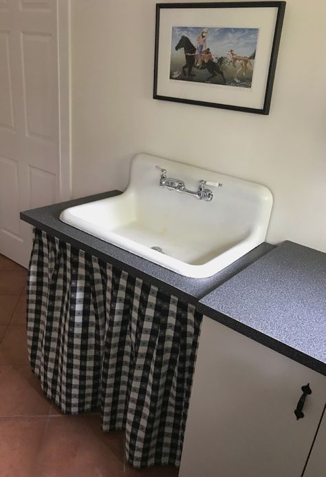 large white farmhouse sink with black and white checked curtain below New House Look Old, Light Fixtures Vintage, Vintage Flooring, Best Farmhouse Sinks, Laundry Chute, Laundry Room Sink, Vintage Doors, Vintage Light Fixtures, Vintage Hardware