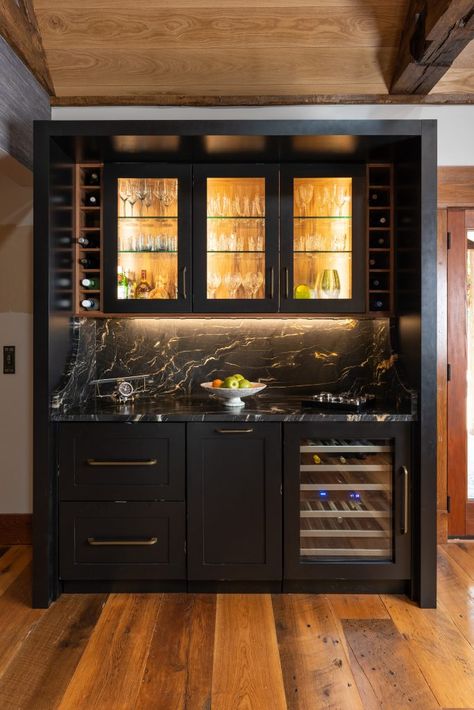 A stunning home bar with custom black cabinets and walnut interiors. The top cabinets have glass panels with interior lighting. A true work of art. #homebarcabinets #blackhomebar #moodyhomebar #custombarlighting Bar With Glass Upper Cabinets, Moody Home Bar Design, Dark Home Bar Ideas, Moody Wet Bar Ideas, Bar Closet Ideas Built Ins, Bar Lounge Design Home, Moody Dry Bar, Black Cabinets Bar, Gentelman Bar