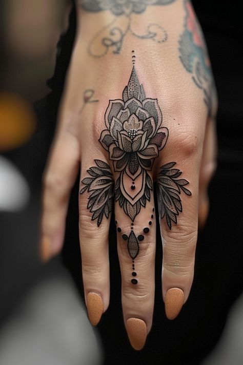 Hand with an intricate black and gray flower tattoo covering the entire back, extending to the middle finger, adorned with detailed patterns and dots. Thumb Palm Tattoo, Womens Thumb Tattoos, Rock Hand Sign Tattoo, Woman Knuckle Tattoos, Finger Tattoos Taurus, Finger Mandala Tattoo, Funny Hand Tattoos, Whimsical Hand Tattoo, Flower Finger Tattoos For Women