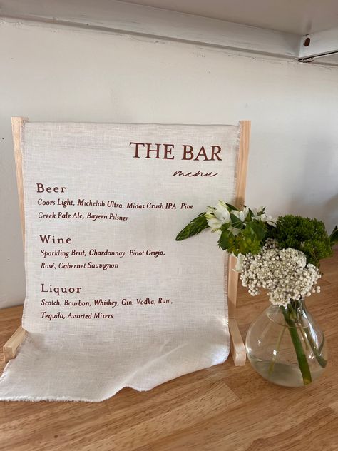 Showcase your bar selection with our semi-customizable Fabric Bar Sign. A timeless addition to your special day. Crafted with premium 100% cotton linen fabric, and customizable for your exact menu. Its versatile design seamlessly complements any wedding theme, making it the perfect focal point for your bar.  Tailor the look to your unique style by choosing from a curated selection of fonts. Select your fabric and font colors to seamlessly blend with your wedding theme. Please note that each Fabric Wedding bar Sign is meticulously crafted to perfection. To ensure the highest quality and attention to detail, we require a 7-day order processing time. We appreciate your patience as we dedicate the time needed to create a unique feature that will be cherished for a lifetime. Standard Dimensions Fabric Bar Sign Wedding, Fabric Bar Menu Wedding, Linen Bar Sign Wedding, Fabric Bar Sign, Linen Bar Sign, Wedding Bar Menu Ideas, Wedding Bars, Fabric Sign, Bar Sign Wedding