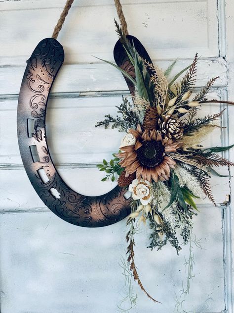 Multi media equestrian art for your home or doorway with different layers of embellishments that add unique beauty and sophistication.  Made for horse lovers in Mind!  LeAther Patterned good Luck Wreath that is both Rustic and Beautiful. Rustic Look with a contemporary  floral spray.  Makes a great Housewarming gift or even a memorial Wreath. I offer many different decorated versions of wood horse heads from fall to spring/summer to Christmas. Message me for links. :-) NEED CUSTOM COLORS? Just a Horse Shoe Door Wreath, Decorating With Horse Shoes, Rustic Western Christmas Decor, Horse Shoe Decor Ideas, Western Wreaths Rustic, Horse Collar Decor Ideas, Wreath With Antlers, Horse Shoe Decor, Rustic Cowboy Decor