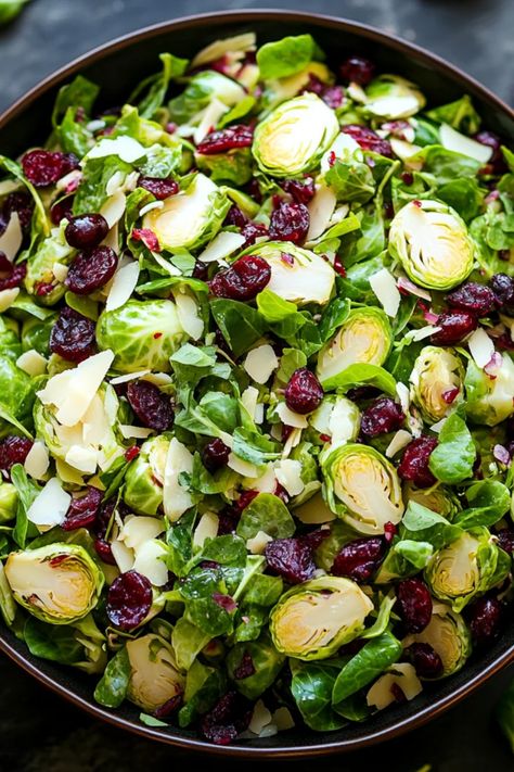 A fresh and crunchy Brussels sprouts salad featuring cranberries and almonds for a delicious and healthy side dish. This pin showcases the vibrant colors and textures of a simple yet flavorful salad made with freshly shaved Brussels sprouts. Shaved Brussel Salad, Brussel Sprout Salad With Pomegranate, Roasted Brussel Sprout Salad Recipes, Shaved Brussels Sprout Salad, Christmas Brussel Sprout Salad, New Years Eve Salad, Salad With Brussel Sprouts, Salad With Cranberries And Almonds, Raw Brussel Sprouts