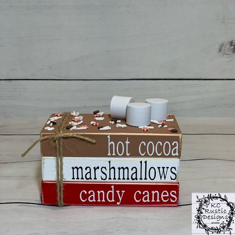 "This adorable Christmas mini wood book stack will be an exceptional addition to all your Christmas decor! These wood blocks are handpainted brown, white and red. I then use high quality vinyl for the wording. On top of the book stack are faux sprinkles and marshmallows. The blocks are then sprayed with a sealant for longevity. Goes great on tier trays and pairs with Rae Dunn. These are adhered together. It is approximately 4\"×2.25\"×2.5\" Please visit my shop for other great items! I also offe Christmas Book Stacks, Wooden Books Christmas, Diy Wooden Book Stacks Christmas, Christmas Wood Block Books, Diy Wood Books, Christmas Mini Book Stack, Marshmallow Crafts, Tray Decor Christmas, Farmhouse Christmas Tree