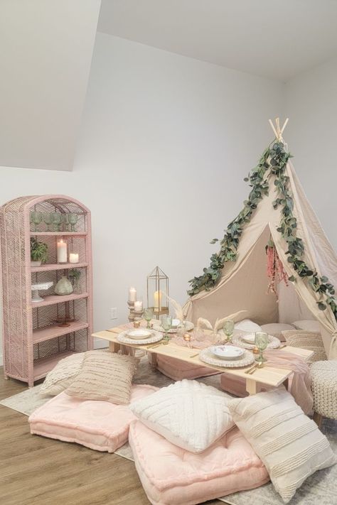 Boho picnic with low tables, pink cushions, white pillows, place settings, decor, a teepee, and a pink shelf. Indoor Picnic Ideas For Kids, Pop Up Picnic Ideas, Pop Up Picnic Business, Boujee Party, Sleepover Business, Indoor Picnic Party, Pink Teepee Party, Pink Tent Sleepover, Pop Up Picnic