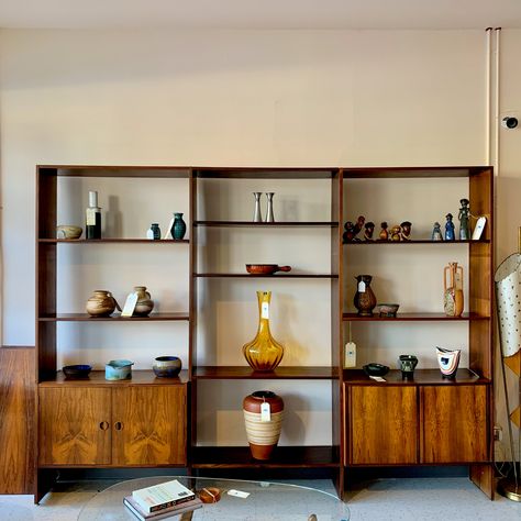 A gorgeous 3 section Danish Modern free standing wall unit by France & Son. This Mid-Century Modern wall unit features ample storage and an open, streamlined design. Completely modular, the individual shelves and storage units are adjustable. Allowing you to create the combination which works most effectively for you. The 4 Brazilian rosewood uprights/ rails provide ample strength and stability. Incredibly elegant and open, the unit provides endless storage options while maintaining a sense of openness in the room. The 2 large box units are varied in style; enabling more storage. One is a tambour door bar cabinet. The second has 2 outward opening doors and adjustable and removable shelf. Wonderfully narrow at only 16 inches in depth. Perfect for almost any room in your home. Easily used in Cream Sofa Living Room, Mid Century Wall Unit, Modern Wall Unit, Shelves And Storage, Tambour Door, Modern Wall Units, Free Standing Shelves, Cream Living Rooms, Door Bar