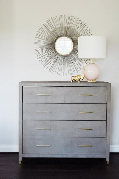 A black sunburst mirror is mounted over a gray dresser accented with brass pulls lit by a pink glass globe Bedroom Ideas Pink, Gray Dresser, Nailhead Headboard, French Headboard, Dresser Makeovers, Space Themed Room, Grey Dresser, Dresser Design, Transitional Bedroom