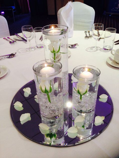 White rose centrepiece Single Rose Centerpiece With Candles, Rose Floating Candle Centerpiece, White Rose In Water Centerpiece, White Rose Floating Candle Centerpiece, White Flower Fairy Light Wedding Centerpieces, Roses In Water Centerpiece Floating Candles, Water Beads Centerpiece, Cylinder Centerpieces, White Rose Centerpieces