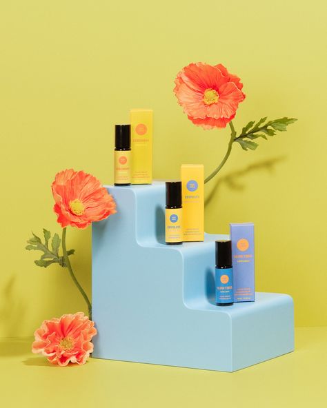 3 aromatherapy oils on a blue prop shaped like a set of stairs - with three levels. There are orange poppies around the stairs and the backdrop is a chartreuse color. The aromatherapy oils are from Thought Sanctuary. Bright Colorful Product Photography, Product Photography Trends 2023, Props Product Photography, Color Block Product Photography, Conceptual Product Photography, Product Photography Colorful, Colourful Product Photography, Bright Product Photography, Retro Product Photography