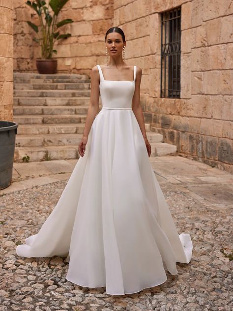 If it’s classic elegance you’re searching for, the Moonlight Tango T133 wedding dress is a luxe choice for your big day. Constructed in organza and satin fabrics that offer contrasting textures, this exquisite gown has a dreamy, ethereal look and feel that’s fitting for a black tie fairytale wedding or a more modern, minimalist event. This design boasts a sleeveless, fitted bodice in smooth satin fabric with a chic square neckline, wide straps that provide comfort and support, and a low scoop Square Neckline Wedding Dress, Square Neck Wedding Dress, Bodice Wedding Dress, Satin Fabrics, Stylish Wedding Dresses, Aline Wedding Dress, Pretty Wedding Dresses, Exquisite Gowns, Minimalist Wedding Dresses