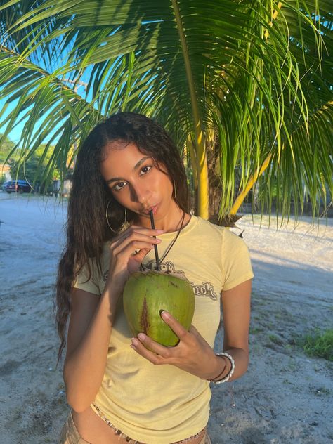 Coconut, coconut trees, island girl, island vibes, island aesthetic, coconut girl, waist beads, island outfit, wavy hair, natural makeup, relaxing vibes, aesthetic pic, tan, palm trees, sand, beachy vibes, beach, yellow tee, y2k graphic tee, drinking coconut Aesthetic Coconut Girl, Aesthetic Coconut, Island Aesthetic, Puerto Rico Vacation, Island Outfit, Coconut Trees, Beachy Vibes, Letter X, Waist Beads