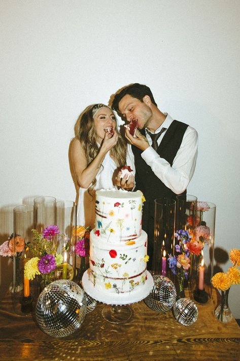 Retro & Colorful Micro-Wedding at the Doyle. Newlyweds feed eachother the wedding cake 60s Wedding Theme Vintage, Retro Winter Wedding, Moody Retro Wedding, Retro Wedding Bouquet, Eclectic Wedding Cake, Funky Formal Wedding, 70s Wedding Photos, Funky Wedding Decor, 70s Wedding Cake