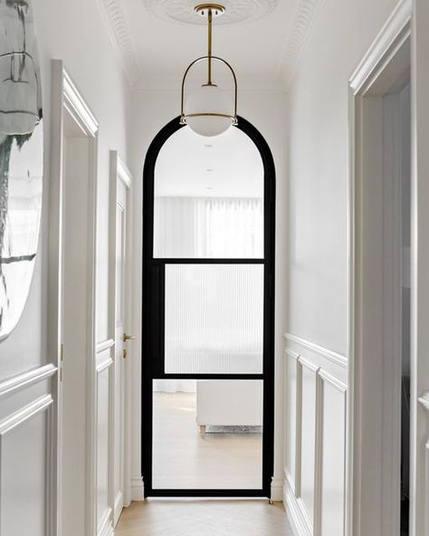 Jen Young on Instagram: "Marking the transition between the old and new of our ‘Laurel Abode’ project, an arched steel door with fluted glass panes feature in the hallway — one of our favourite features in the home. As shared in our @houseandgarden feature, aesthetically, it just takes your breath away; from a functionality perspective, it draws light into the dark hallway and helps with soundproofing and temperature control in the bedrooms at the front of the house. To read more, pic up an is Arch Glass Door Interior, Arch Hallway Ideas, Glass Doors Interior Modern Hallways, Arched Steel Doors, Fireplace Between 2 Doors, Fluted Glass Arch Door, Glass Hallway Door, Arch Bedroom Door, Glass Door Hallway