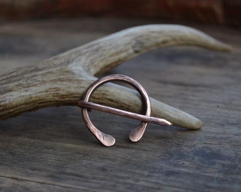 .:.  Copper penannular brooch .:.  I handforged this shawl pin from a really thick piece of recycled copper. This listing is for the smaller one of the three in the photos. A sturdy miniature pin, for small shawl. Penannular ("Annular" means formed as a ring and "penannular" formed as an incomplete ring) brooches feature a long pin attached by its head to a ring; the pin can move freely around the ring as far as the terminals. There is a gap between the terminals wide enough for the pin to pass Wire Wrapped Stone Jewelry, Shawl Pin, Hammered Earrings, Wire Wrapping Stones, Iron Age, Anglo Saxon, Shawl Pins, Viking Jewelry, Stone Jewelry