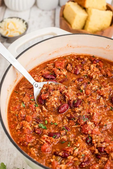 Close up shot of a Dutch Oven turkey chili with a spoon dipping in. Turkey Chili Dutch Oven Recipes, Dutch Oven Turkey Chili, Turkey Chili Dutch Oven, Chili Dutch Oven, Dutch Oven Turkey, Dutch Oven Chili Recipe, Using Leftover Turkey, Oven Turkey, Dutch Oven Chili