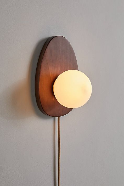 Refresh your lighting display with this statement sconce featuring a sculptural wood base topped with a milky glass shade. Plugs in to power on. Available exclusively at Urban Outfitters. Features Statement sconce from our Yoji lighting collection Sculptural base Milky glass shade Plug in UO exclusive Content + Care Wood, iron Wipe clean Imported Made in compliance with US electrical standards. To use this item outside of the US, pair with an outlet adapter and voltage converter made specifically for use in your location. Size Wattage/Voltage: AC 120V/60Hz Overall dimensions: 11.3" l x 7.4" w x 6.5" h | Yoji Sconce in Brown at Urban Outfitters Luminaria Diy, Plug In Pendant Light, Retro Lampe, Minimalist Lighting, Wall Sconces Bedroom, Sconces Bedroom, Age 50, Organic Forms, Tropical Party