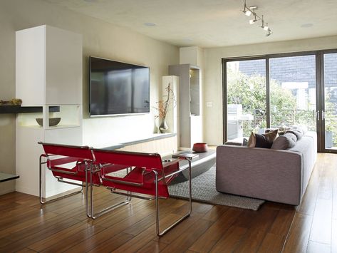 Modern home with Living Room, Sofa, Chair, Medium Hardwood Floor, and Rug Floor. The living room is furnished with Wassily chairs by Marcel Breuer, a Limbo coffee table from Roche Bobois, and a Reid sofa from Design Within Reach. Photo  of Marcel Breuer Designs in Modern Homes Wassily Chair Living Room, Red Chair Living Room, Ultra Modern Living Room, Black And Silver Living Room, Marcel Breuer Wassily Chair, Marcel Breuer Chair, Breuer Chair, Wassily Chair, Condo Living Room