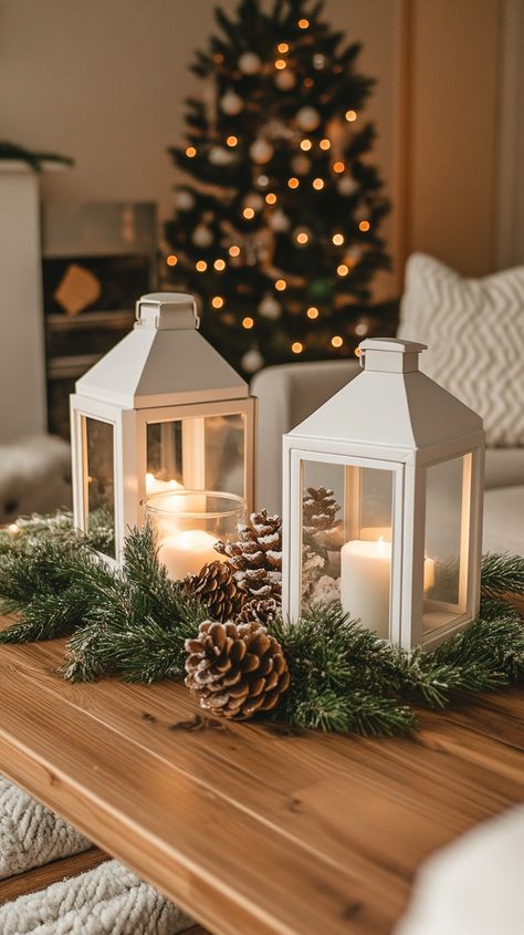 Cozy living room coffee table adorned with white lanterns, pine cones, greenery, and soft winter lighting decorations. Winter Lantern Decor, Cozy Coffee Table, Living Room For Christmas, Winter Retreat, Christmas Decorating Ideas, White Lanterns, Winter Decorations, Cozy Coffee, Christmas Decorations Living Room