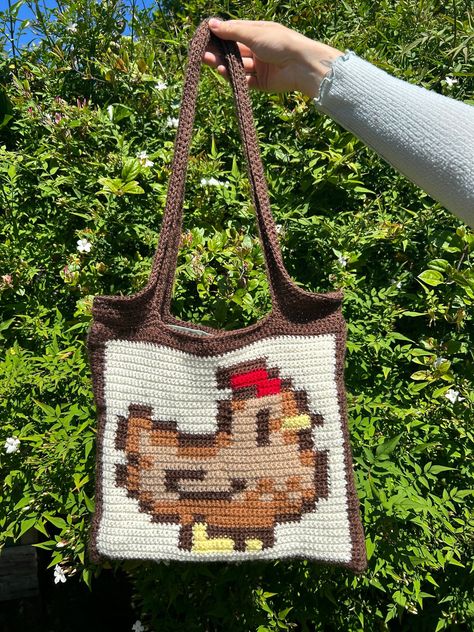 ✨Make your own crochet Stardew Valley chicken tote bag!✨ 📏 The main body of this bag is approximately 32.5cmx28cm, and the length of the handles measured from the top of the bag is approximately 31cm 📏 ✍🏼Part of this pattern includes instructions that have been written out in 3 different ways 1. Stitch Fiddle Graph  2. Colour Block Instructions  3. Written Instructions  🧶Materials needed:🧶 - 4mm crochet hook (can use other sizes at your own discretion) - Dowel rod - Scissors - Darning needl Stardew Valley Chicken Crochet, Stardew Valley Crochet Pattern Free, Stardew Valley Crochet Pattern, Crochet South Park, Crochet Stardew Valley, Stardew Valley Crochet, Crochet Pouch Pattern, Stardew Valley Chicken, Stitch Fiddle