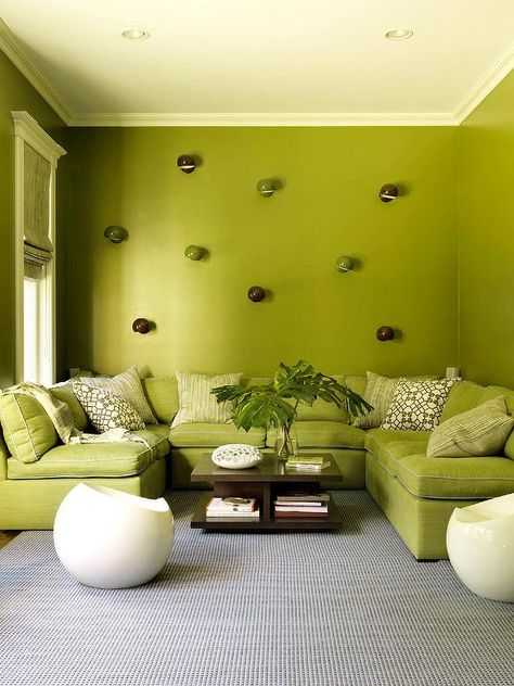 Modern avocado green living room features a brown wooden coffee table in front of a green u-shaped sectional with brown trellis pillows against a green wall. Modern Green Living Room, Living Room Color Schemes, Coastal Living Rooms, Green Walls, Room Color Schemes, Living Room Green, Upholstered Sectional, Green Interiors, Green Rooms