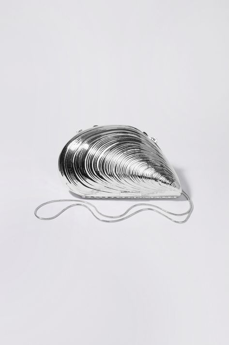 SPRING 2023 ACCESSORIES The Bridget Metal Shell Clutch in Silver. Cast from metal and designed as a hardshell clamshell case elegantly shaped like an oyster. Tonal satin lined interior, and chain shoulder strap. SIMKHAI Women's Bridget Metal Shell Clutch in Silver, Satin Metal Clutch Bag, Rocky Rihanna, Seashell Clutch, Edgy Interior Design, Edgy Bridal, Shell Clutch, 2023 Accessories, Metal Purse, Perfect White Tee