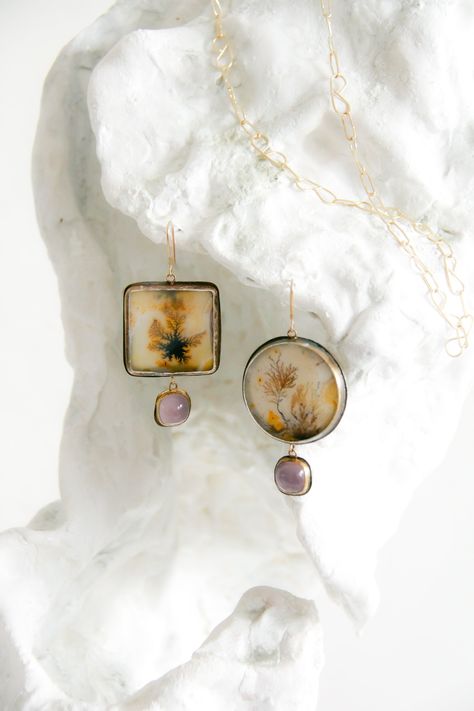 This elegant statement pair is a marriage between earthy golden dendritic agates and glowing lilac chalcedony. I love a good mismatched pair and I think these special stones sing gracefully together. One of a kind, these earrings are set in fine silver and 18k gold bezels on sterling silver backs with 18k gold ear hooks and connectors. Materials: dendritic agate, chalcedony, 18k yellow gold, .925 sterling silver, .999 fine silver Measures 70mm overall earring length. Send me a direct email at hello@lorifrancescutti.com with any questions about this or another piece. Dendritic Agate Jewelry, Chalcedony Earrings, Dendritic Agate, Shades Sunglasses, Agate Jewelry, Gift Bundles, Metallic Accents, Instagram Shop, Fine Silver