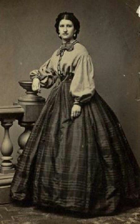 A lady in a Garibaldi blouse with plaid skirt. Wonder what color the Garibaldi is? 1860s Dresses, Victorian Era Fashion, 1860 Fashion, Modern Gown, 19th Century Clothing, Period Outfit, Century Clothing, Old Fashion, Historical Dresses