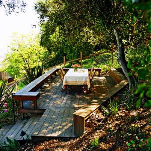 Taming a slope    A deck at the top of this sloping backyard transformed the space into an inviting destination for taking in the view.    The rear edge of the 15- by 24-foot deck notches into the hill. A low retaining wall holds the uphill section in place and doubles as another bench seat. Steep Backyard, Sloped Yard, Sloped Backyard, Hillside Landscaping, Sloped Garden, Fire Pit Area, Decks Backyard, Backyard Deck, Outdoor Deck