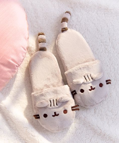 Pusheen Plush Slippers lying on a white fluffy surface next to a light pink pillow. Plush slippers have Pusheen's face embroidered accompanied by ears that extend off the toe box. Off the back of the slippers are Pusheen's striped tails. Pusheen Pajamas, Pusheen Clothes, Pusheen Costume, Pusheen Slippers, Pusheen Merch, Pusheen Stuff, Cute Pusheen, Pusheen Collection, Room Slippers