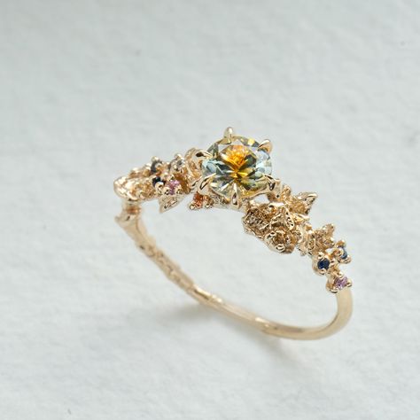 The ethereal and enchanting dahlia, sweetly pulled from a peachy fairytale. Featuring a 5mm parti Montana sapphire— each stone a one-of-a-kind, natural blend of peach/apricot and silvery/greenish hues. Just like the dahlias that inspired it, the sapphires’ swirling hues are dreamy and glistening. Features a 5mm “kaleidoscope” Montana Parti sapphire (each stone is unique, with peach and silvery/greenish hues)A sprinkling of a 0.9mm orange sapphire, 1mm orange sapphire, 1.2mm orange sapphire, 1mm Cottagecore Wedding Ring, Earthy Wedding Rings, Laurie Fleming, Light Blue Sapphire, Cute Engagement Rings, Future Engagement Rings, Montana Sapphire, No Code, Dream Engagement Rings