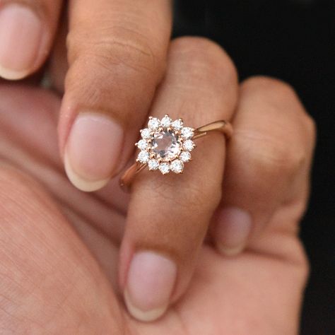 A romantic pink Morganite set in multiple prongs, with a unique round diamond halo, this floral cluster engagement ring is definitely a stunner and a keeper! The flower, mounted on a cathedral gold tapered band renders an old world charm with a fresh look. A perfect alternate engagement ring! * Centre Stone : Morganite * Stone Shape : Round (5 mm) * Stone Wt.: 0.40 Ct. * Diamond : Round Cut * Diamond Wt. : 0.27 Ct. * Color-Clarity Grade : H-I, Vs Si * Gold - 14kt, 2.3 grams Solid gold (approx.) Flower Shape Engagement Ring, Unique Engagement Rings Pink, Floral Halo Engagement Ring, Vintage Floral Engagement Ring, Engagement Rings Floral, Flower Wedding Rings, Flower Shaped Engagement Ring, Engagement Ring Flower, Flower Cluster Ring