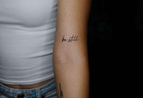 Be Still Arm Tattoo, Be Still Tattoo Font Simple, Upper Elbow Tattoos For Women, Meaningful Rib Tattoos For Women, Be Still And Know That I Am God Tattoo, Be Still Tattoo Font, Peace Be Still Tattoo, Be Still And Know Tattoo, Minimalist Writing