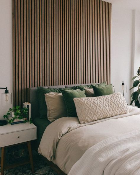 a boho bedroom with a stained wood slat wall, a bed with green and neutral bedding, white nightstands, potted greenery Wood Panel Bedroom, Monochromatic Living Room, Wall Behind Bed, Bench Dimensions, Feature Wall Bedroom, Wood Slat Wall, Wall Panels Bedroom, Slatted Headboard, Accent Wall Bedroom