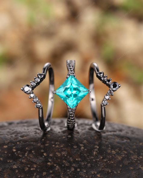 ► FEATURES Rhodium black plating: Rhodium is a precious metal that is in the family of platinum. There are many upsides of rhodium plated jewelry. Center Stone:  3 carat lab created Paraiba tourmaline, 7x7 mm princess cut. Side Stone: 0.2 Carat Black Moissanite  *Band Width (Bottom): 1.6-1.7mm Wedding band:(2PCS) *Accent stone: 0.6 Carat Black Moissanite  *Band Width (Bottom): 1.6-1.7mm The center stone of the ring can be replaced with other different kinds of gemstone such as morganite, aquamarine, amethyst, citrine, opal, moissanite, alexandrite, moss agate, etc. If you want to customize your own personal ring, please feel free to contact me. ► PROCESSING & SHIPPING Processing time: 3 to 4 weeks after placing order, International Buyers Please Note: In some cases, additional custom fees Purple Wedding Rings, Black Gold Engagement Rings, Gothic Engagement Ring, Tourmaline Engagement Ring, Black Gold Ring, Moissanite Band, Princess Cut Gold, Future Engagement Rings, Alexandrite Engagement Ring