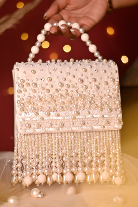 White premium satin clutch bag with envelope flap, beads, pearls, glass beads embellishment, pearl drops tassels and beaded handle. Type:  Beads, Pearl Drops, Pearls and Glass Beads Embellished Composition: Premium Satin Color: White Other Details:  Pearl drops fringe tassels Back placement embellishment Closure: Magnet button Dimensions L x H x W (in inch): 6.5 x 6 x 2  - Aza Fashions Charm Bracelets For Girls, Embellished Purses, Embroidery Purse, Diy Fabric Jewellery, Beaded Clutch Bag, Hand Beaded Embroidery, Hand Embroidery Dress, Embellished Clutch, Diy Bags Patterns