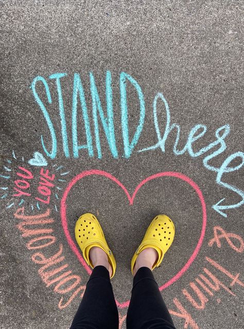 Stand here and think about someone you love. Yellow crocs. Interactive Chalkboard Ideas, Chalk Quotes Sidewalk, Positive Chalk Messages, Chalk Art Positive Messages, Inspiring Chalk Art, Kindness Chalk Art, Encouraging Chalk Art, Mental Health Chalk Ideas, Teacher Appreciation Chalk Art