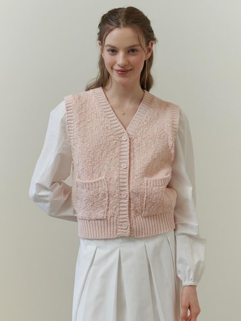 The garment is a sleeveless knitted vest with a V-neckline and front button closure. The knit texture is prominently visible, indicating a cozy, tactile feel. It also features ribbed detailing along the neckline, armholes, and hem, providing a neat and finished look.- The vest includes two front pockets which add practicality and a casual element to the design.- Its relaxed fit suggests it can be layered over various outfits for added warmth.- The ribbed details enhance the fit and contribute to the vest's classic style. Vest Over Dress, Sleeveless Cardigan Outfit, Pink Knit Vest, Sleeveless Knitted Vest, Knit Vest Outfit, Knit Texture, Candy Floss, Knitted Vest, Pink Knit