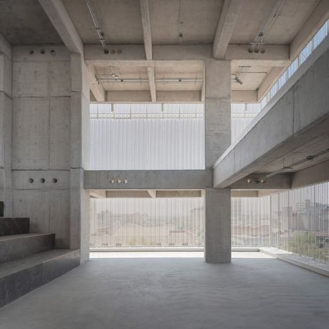 The concrete slab superstructure has been left raw, with glimpses of the slim pillars and beams through the metal. Light filters through to the interiors, unobstructed by concrete outer walls. Metal Facade, High Building, Light Filters, Concrete Pool, Spanish Architecture, Exposed Concrete, Concrete Structure, Concrete Slab, Metal Light