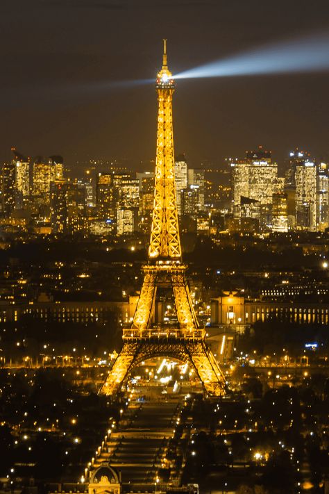 View of Eiffel Tower at night from Tour Montparnasse, with its beacon light piercing the dark sky. The Parisian cityscape glows with lights stretching towards the horizon, highlighting the contrast between the landmark and the urban environment. Paris Travel Wardrobe, Aesthetic Map, Eiffel Tower Night, Parisian Picnic, 4 Aesthetic, Eiffel Tower At Night, Paris Itinerary, Paris Travel Tips, Paris Travel Guide