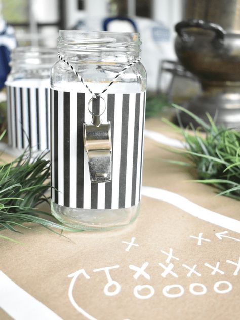 I had so much fun creating this football themed tablescape for my dinner club this month! I used lots of things I already had on hand and got creative with ways to use them for this tablescape. A memorobilia football helmet that my husband had, an old football, a yellow scarf turned into "penalty" flag napkins, and black/white striped paper and whistles to create "referee" glasses made perfect accents for my table. Read along and I'll show you how I created this tablescape on a budget. Football Table Scape, Sport Table Decorations, Sports Themed Retirement Party, Football Party Tablescape, Classy Football Decor, Sports Table Decorations, Boho Football Party, Football Bridal Shower Theme, Football Theme Engagement Party