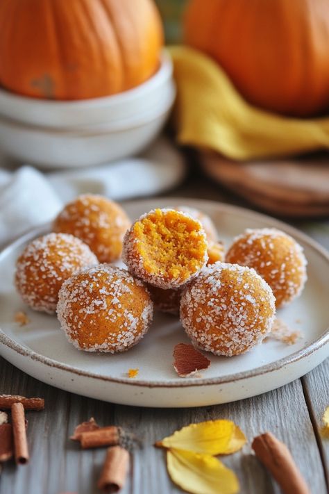 Pumpkin spice truffles coated in sugar, with a bite taken out of one, on a rustic wooden table. Pumpkin Pie Energy Bites, Pumpkin Spice Energy Balls, Pumpkin Spice Balls, Pumpkin Pie Balls, Pumpkin Energy Bites, Pumpkin Energy Balls, Healthy Pumpkin Cheesecake, Coconut Energy Balls, Pumpkin Balls