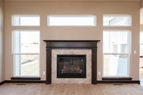 Traditional fireplace with wood mantle surround and transom windows. Skogman Homes - Cedar Rapids, Marion, Iowa. #fireplace #traditional #newhome Fireplace Window Above, Windows Above Fireplace, Modern Transom Windows, Fireplace With Wood Surround, Fireplace Ideas With Windows On Side, Window Over Fireplace, Fireplace With Window Above, Fireplace Windows, Wood Mantle Fireplace