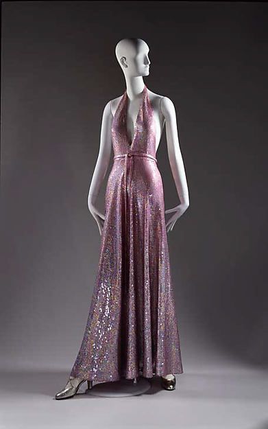 Evening dress, Halston, 1974: This dress incorporates the popular style of a halter neck line and glamorous, flashy sequined fabric into a sleek, fluid design. Mode Disco, Halston Vintage, Fashion History Timeline, Halston Dress, Fashion 1970s, Fashion Queen, 20th Century Fashion, Vintage Gowns, Vintage Mode