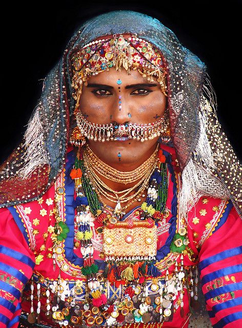 A male dance performer from desert Cholistan wearing traditional cloth  and jewelry common in that part of Pakistan. This desert is also known  as Rohi.People in this place live by moving one place to other in  search of food and water.It is about 30km away from Pakistani city  Bahawalpur and comprises 16000 sq km.Extends to Thar desert and Sindh  Province of Pakistan and into India. Cholistan Desert, Cultural Dress, Traditional Festival, Indian Subcontinent, Festival Costume, Uk Destinations, Facial Expression, We Are The World, South Asia