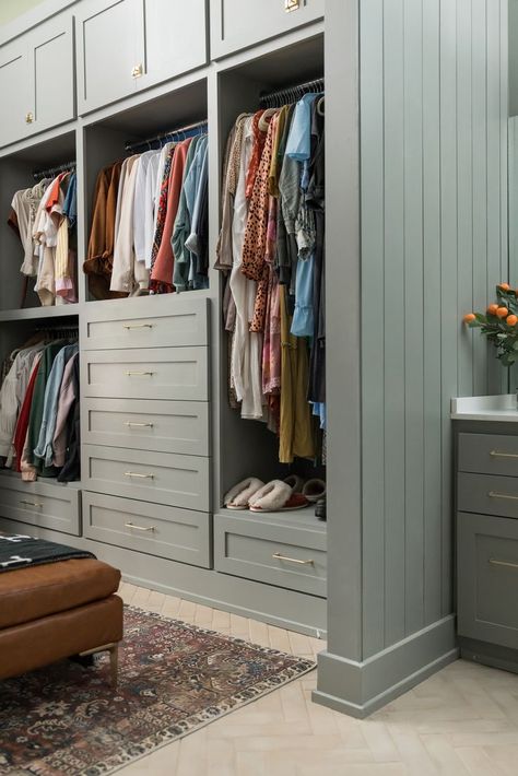 Large closet with hers side with built in shelving, drawers, and racks. Brown leather ottoman with moody warm toned rug. Finished Closet Ideas, Tile In Closet, Custom Closet Color Ideas, Grey Closet Ideas, White Custom Closet, Dresser In Master Closet, Closet Colors Paint Walk In, Small Closet With Window, Painted Walk In Closet